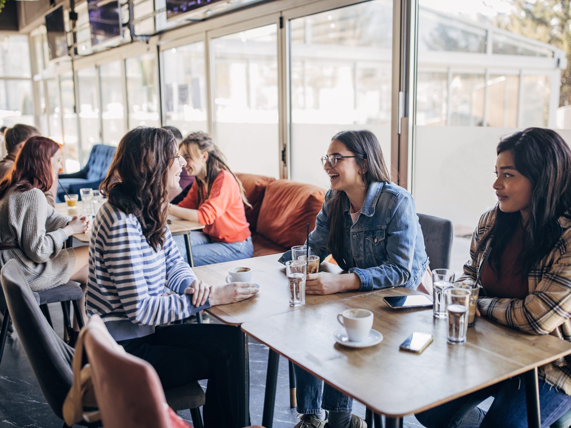 Three women sitting at a table in a coffee shop having a conversation